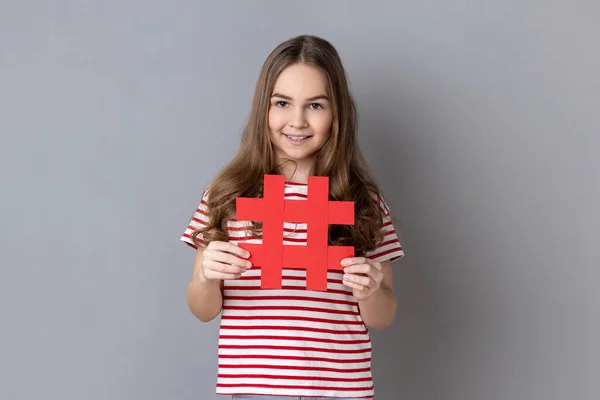 Portrait Happy Little Girl Wearing Striped Shirt Holding Hashtag Symbol — Stockfoto