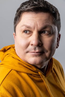 Kendine güvenen yakışıklı bir adamın, sakin bir ifadeyle, erkek sağlık hizmetleri ve güzelliğiyle kentsel kapüşonlu giyinmiş, yakından çekilmiş portresi. Gri arka planda izole edilmiş kapalı stüdyo görüntüleri.