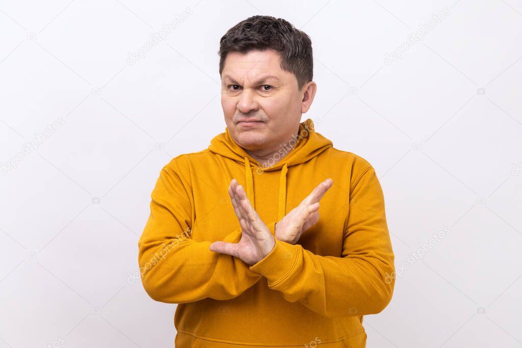 No way, absolutely not. Portrait of middle aged man showing x sign with crossed hands, meaning stop, this is the end, wearing urban style hoodie. Indoor studio shot isolated on white background.