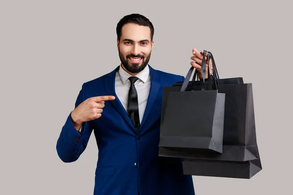 Delighted Bearded Man Pointing Finger Paper Bags Hand Looking Toothy — стоковое фото