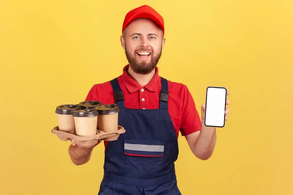 Delivery Man Holding Take Away Coffee Showing Mobile Phone Blank — Zdjęcie stockowe
