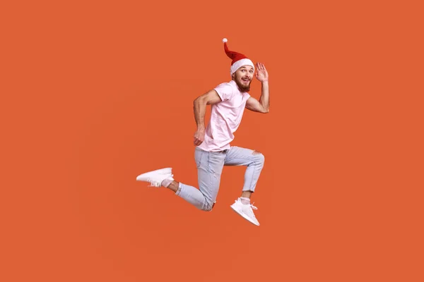 Positive Inspired Bearded Man Santa Hat Jumping Air Running Fast — Stockfoto