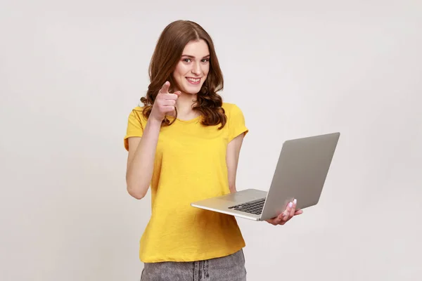 Portrait Optimistic Young Woman Yellow Shirt Holding Laptop Pointing Finger — kuvapankkivalokuva