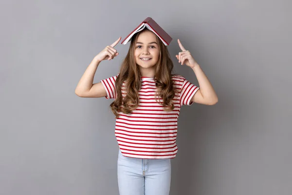 Little Girl Striped Shirt Covering Head Book Smiling Camera Disobedient — Stock fotografie
