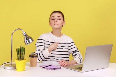 This is me. Self confident egoistic woman office manager pointing herself and looking at camera with arrogant expression, working in office. Indoor studio studio shot isolated on yellow background.