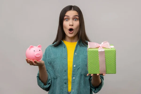 Portrait Amazed Surprised Woman Holding Wrapped Gift Box Piggy Bank — Zdjęcie stockowe