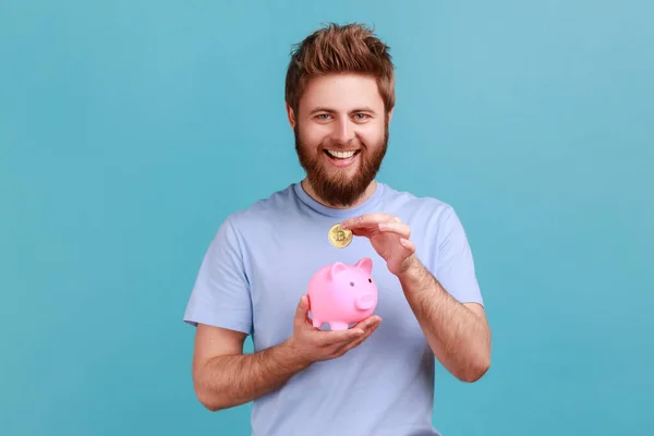 Portrait Happy Smiling Bearded Man Looking Camera Putting Coin Piggybank — Foto Stock