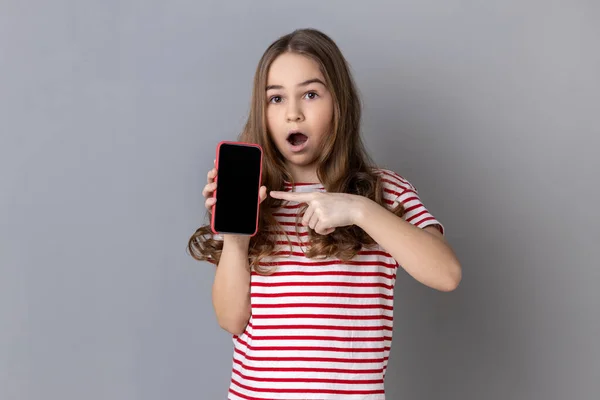 흰색빈 디스플레이가 스마트폰을 가리키는 줄무늬 티셔츠를 소녀의 프로그램에 충격을 받았다 — 스톡 사진