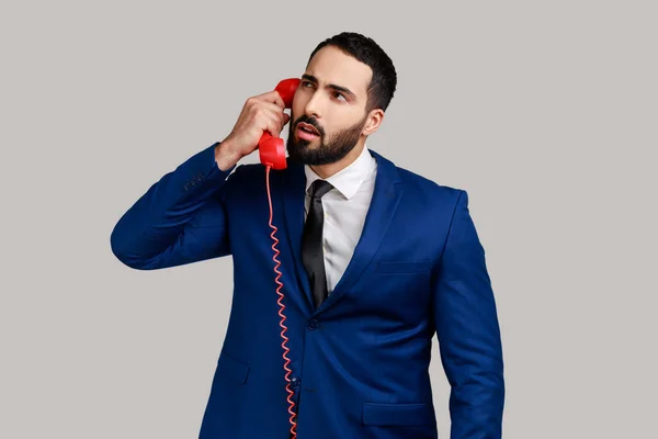 Σκεπτικός Γενειοφόρος Άντρας Που Κρατάει Ακουστικό Του Τηλεφώνου Κάνει Συζητήσεις — Φωτογραφία Αρχείου