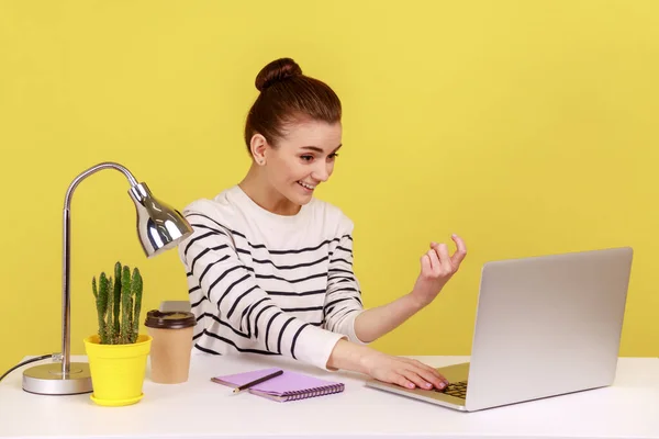 こっちへ来い 女性マネージャーは職場に座って ノートパソコンの画面に表示し ジェスチャーを手招きし 仕事のアプリケーションを提供します 黄色の背景に隔離された屋内スタジオショット — ストック写真