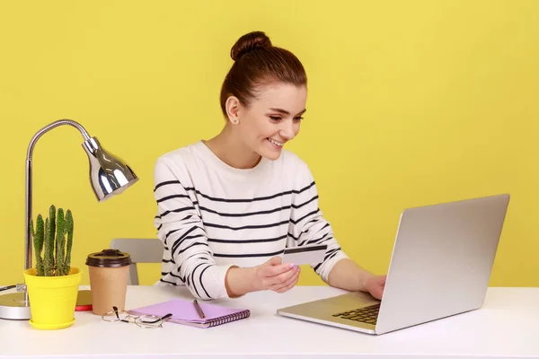 インターネットショッピング 電子商取引 ラップトップで職場に座っている幸せな女性 クレジットカードを保持し オンライン購入を行います 黄色の背景に隔離された屋内スタジオショット — ストック写真