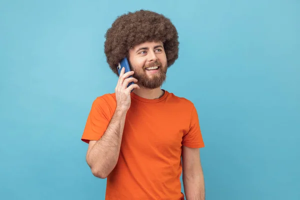 Portret Uśmiechniętego Mężczyzny Fryzurą Afro Pomarańczowym Shircie Mówiącego Przez Telefon — Zdjęcie stockowe
