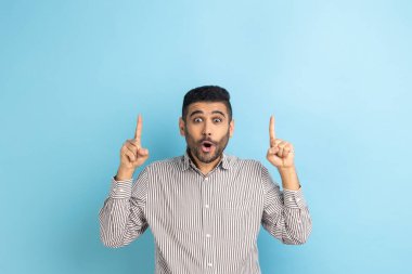 Bak, çılgın bir reklam. Sakallı işadamı, reklam içeriği için boş yeri işaret ediyor ve şaşırıyor, çizgili gömlek giyiyor. Mavi arka planda kapalı stüdyo çekimi.