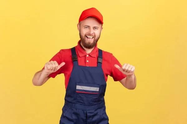 幸せな労働者の男立って 自分自身を指しているの肖像画は 彼の仕事の結果に満足して 全体と赤のキャップを着ている 黄色の背景に隔離された屋内スタジオショット — ストック写真