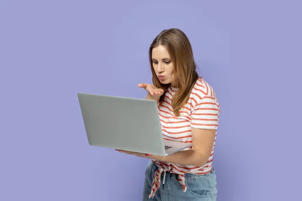 낭만적 긍정적 여성의 줄무늬 티셔츠를 노트북에서 일하고 디스플레이를 비디오 전화를 — 스톡 사진