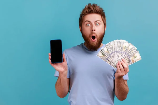 기사보기 수염을 잘생긴 남자가 지폐를 화면으로 온라인 도박을 휴대폰을 소지하고 — 스톡 사진