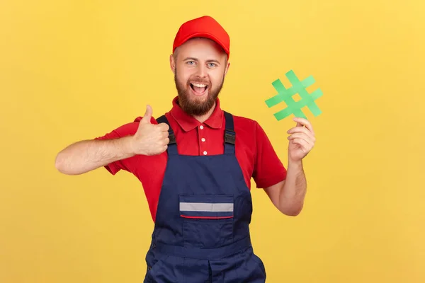 Portrait Excited Handyman Wearing Blue Overalls Standing Holding Green Hashtag — Stock Photo, Image