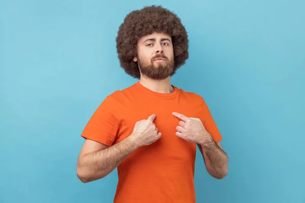 Portrait of man with Afro hairstyle drawing attention to itself, bragging with strength and endure, successful famous person posing at camera. Indoor studio shot isolated on blue background.