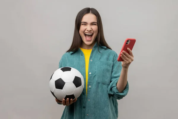 Extremadamente Feliz Mujer Emocionada Pie Sosteniendo Pelota Fútbol Uso Teléfono — Foto de Stock