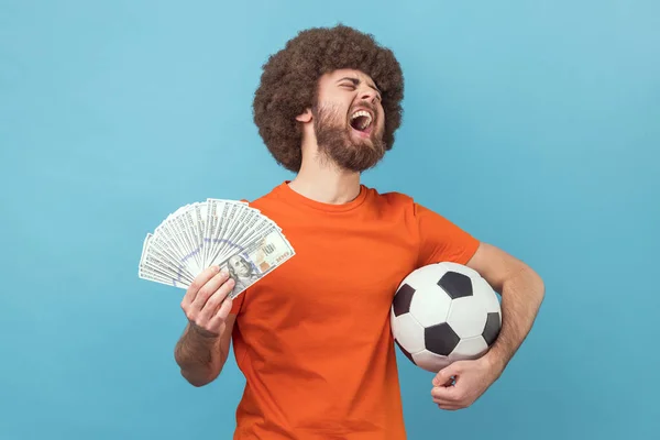 Vzrušený Muž Afro Účesem Oranžovém Tričku Fotbalovým Míčem Stodolarovými Bankovkami — Stock fotografie