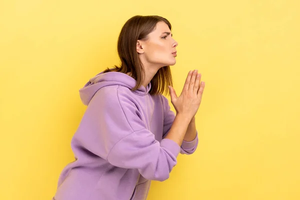 侧观恳求女人保持手臂在祈祷姿态和请求原谅 为错误感到抱歉 穿紫色帽衫 在黄色背景下隔离的室内拍摄 — 图库照片