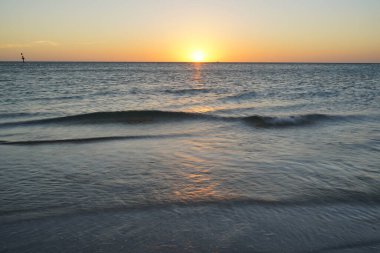 Turuncu gökyüzü ve sakin dalgalarla gün batımı