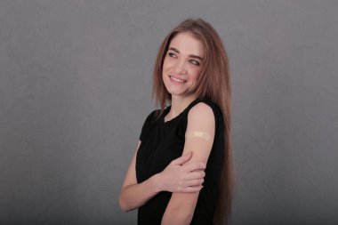 Koronavirüse karşı aşılanmış gülümseyen kız. Omzuna yama