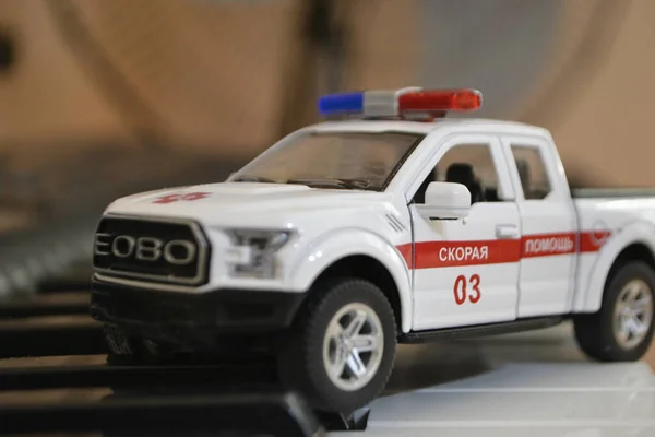 Arabanın metal gövdesinde haç olan bir ambulansın küçük kırmızı ve beyaz koleksiyon modeli.