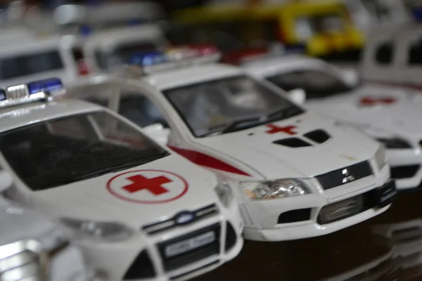 Arabanın metal gövdesinde haç olan bir ambulansın küçük kırmızı ve beyaz koleksiyon modeli.