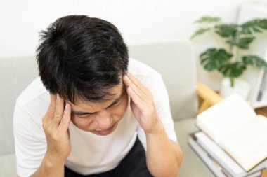 Stresli Asyalı orta yaşlı bir adam baş ağrısı ya da migren krizi belirtileri, baş ağrısı, baş ağrısı, baş dokunuşu, rahatlamak ve gerilimi azaltmak için el ile şakaklara masaj, sağlık sorunları,