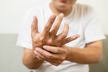 Yaklaş, Parkinson hastalığından titreyen Asyalı orta yaşlı adam, dinlenme sarsıntısı belirtileri, el titremesini kontrol etmek için elini tutan erkek hasta, nörolojik bozukluklar, beyin sorunları, sağlık hizmetleri.