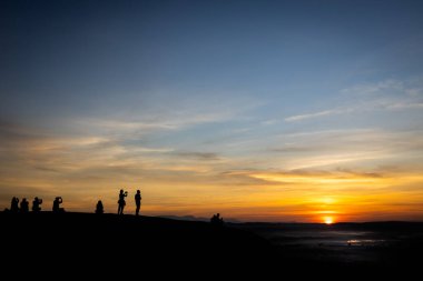Güneşin doğuşuyla fotoğraf çeken turistlerin siluet fotoğrafı, insanlar sabahın ilk ışıklarını ve sisini izliyor, sabahın ilk ışıklarıyla Phu Sing Ulusal Ormanı 'ndaki Three Whale Kayalıkları' nda, Bueng Kan