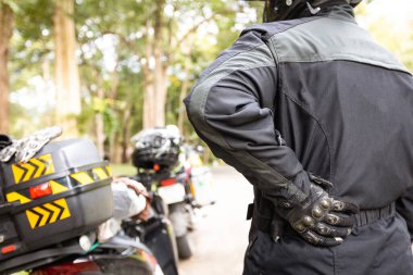 Sırt ağrısı çeken yorgun Asyalı bir adam, ağrılı, ağrılı, erkek binicinin uzun bir motosiklet yolculuğunun ardından sırt ağrısı ve ağrıları var, yanlış oturmaktan ya da uzun süre araba kullanmaktan akut sırt ağrısı çekiyor.