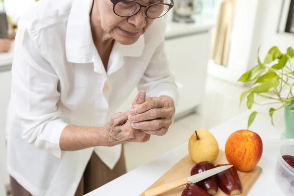亚裔老年妇女食指末端止血 食指上有刀伤 老年妇女在切水果时割伤了手指 家中厨房发生意外受伤 — 图库照片