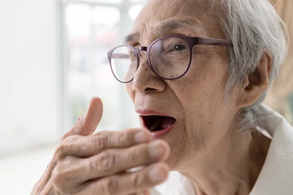 Asian senior woman checking breath with hand,old elderly doing a bad breath test,foul mouth from inside the tongue,teeth and gums  problems,oral bacteria,smelling breath,halitosis,dental care concept