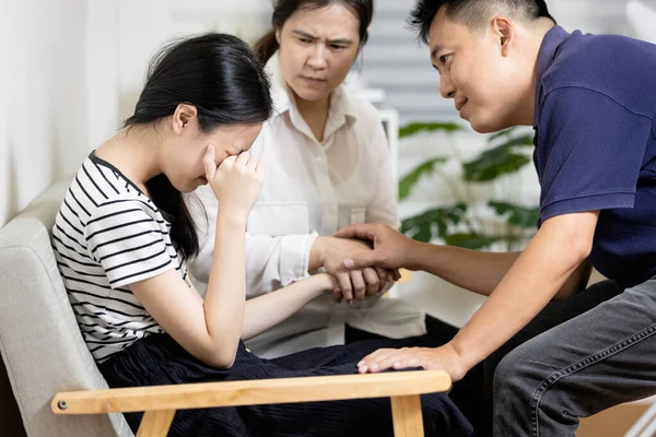 Asian parents give advice,talk sharing thoughts care to teenage girl,mom and dad holding hands to comfort and consoling daughter together,sad teenager student crying at home,family life relationship