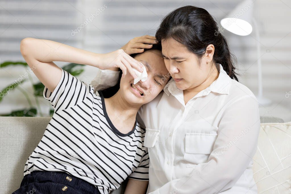 Stressed anxious teenage girl sitting at home crying,worried about mistake and lied to her mother,asian mom was encouraging and forgiving for her repentance and confession,speaks the truth with family