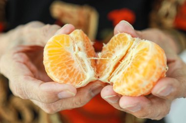 Meyve yakın, ellerinde sulu portakal tutan yaşlı kadın, soyulmuş mandalina gösteren yaşlı kadın, portakal lifinden C vitamini, lezzetli ve iştah açıcı, sağlıklı beslenme, beslenme konsepti