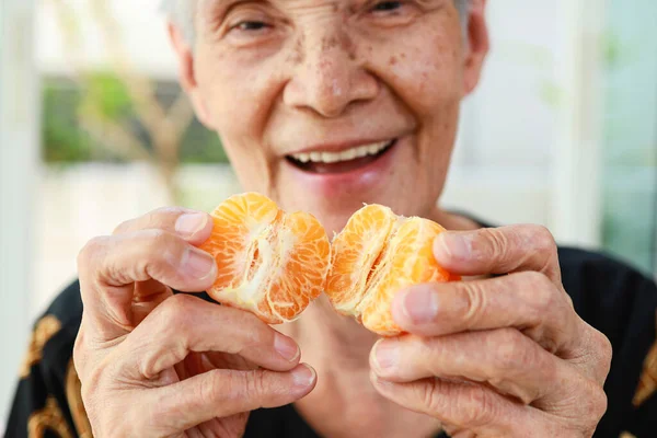 有机水果 手里拿着多汁橙子的老年人 手拿着去皮橘子的老年妇女 桔子纤维中的维生素C 味道鲜美可口 健康饮食 营养观念 — 图库照片