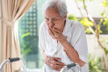 Asyalı son sınıf öğrencisi karın şişliği, karın ağrısı, gaz birikmesi, geğirme, mide bulantısı, kusma, gıda zehirlenmesi, mide ekşimesi, mide yanması, mide sorunu olan yaşlı bir kadın.