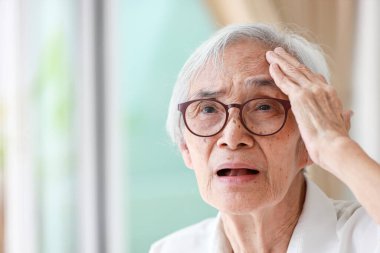 Forgetful asian senior woman with amnesia,brain disease,patient holding head with her hand,suffering from senile dementia,memory disorders,confused old elderly with Alzheimer's disease,health problems
