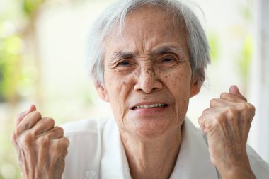 Angry old elderly clenching fists,furious expression on face,showing displeasure,hostility,bad-tempered,feeling irritation,irritable senior woman was indignant,full of anger,aggressive,mood swings