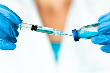 Doctor extrae un fluido médico azul una ampolla en un injejction