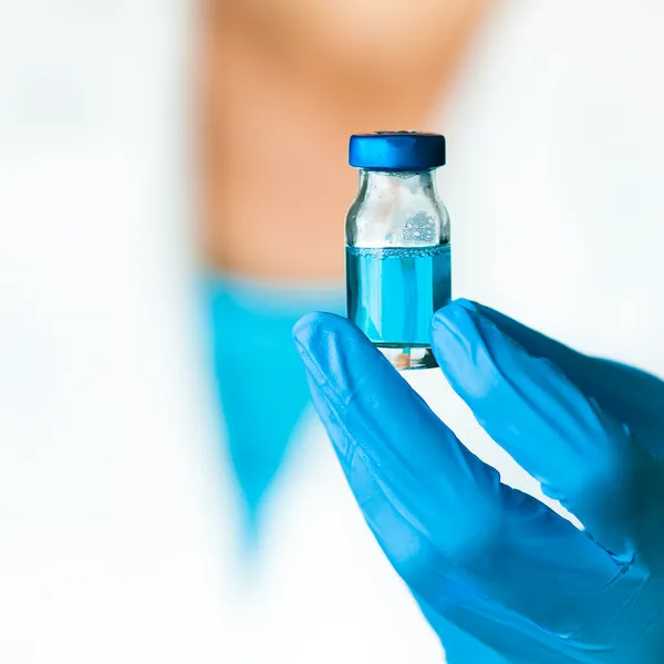 Ένας επιστήμονας κατέχει ένα έντονο μπλε ιατρική υγρό σε μια αμπούλα Φωτογραφία Αρχείου
