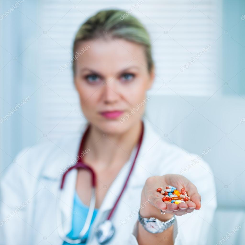 Pretty Young Female Doctor Is Showing a Handful of Medication or Drugs