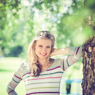 Güzel genç kız tarafından şehir parkındaki ağaç duruyor