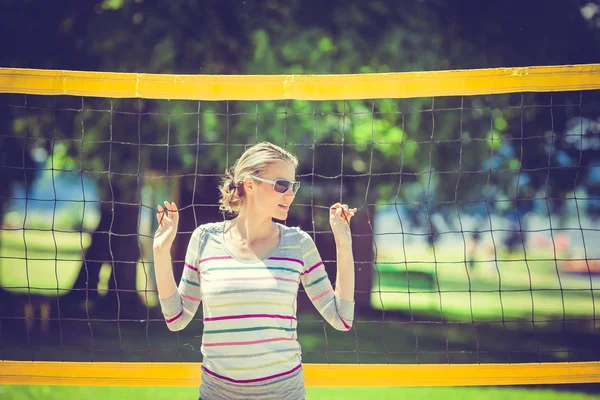 Schöne Frau lehnt am Beachvolleyballnetz während einer Stockbild