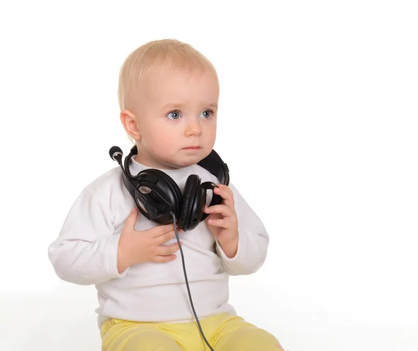 Bébé jouant avec des écouteurs sur fond blanc — Photo