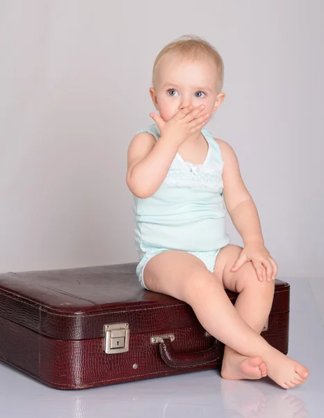 Baby girl playing with suitcase on grey background — Stock Photo, Image