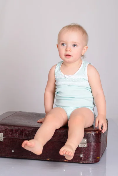 Bébé fille jouer avec valise sur fond gris — Photo